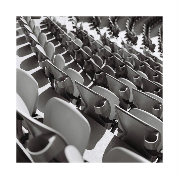 Rows of empty stadium seats are arranged in a diagonal pattern.