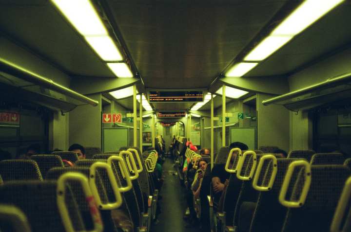 The interior of a train car is visible, with rows of seats and passengers.
