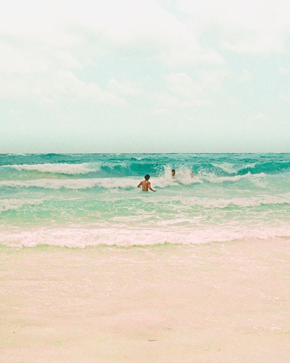Two men are in the ocean with waves crashing around them.