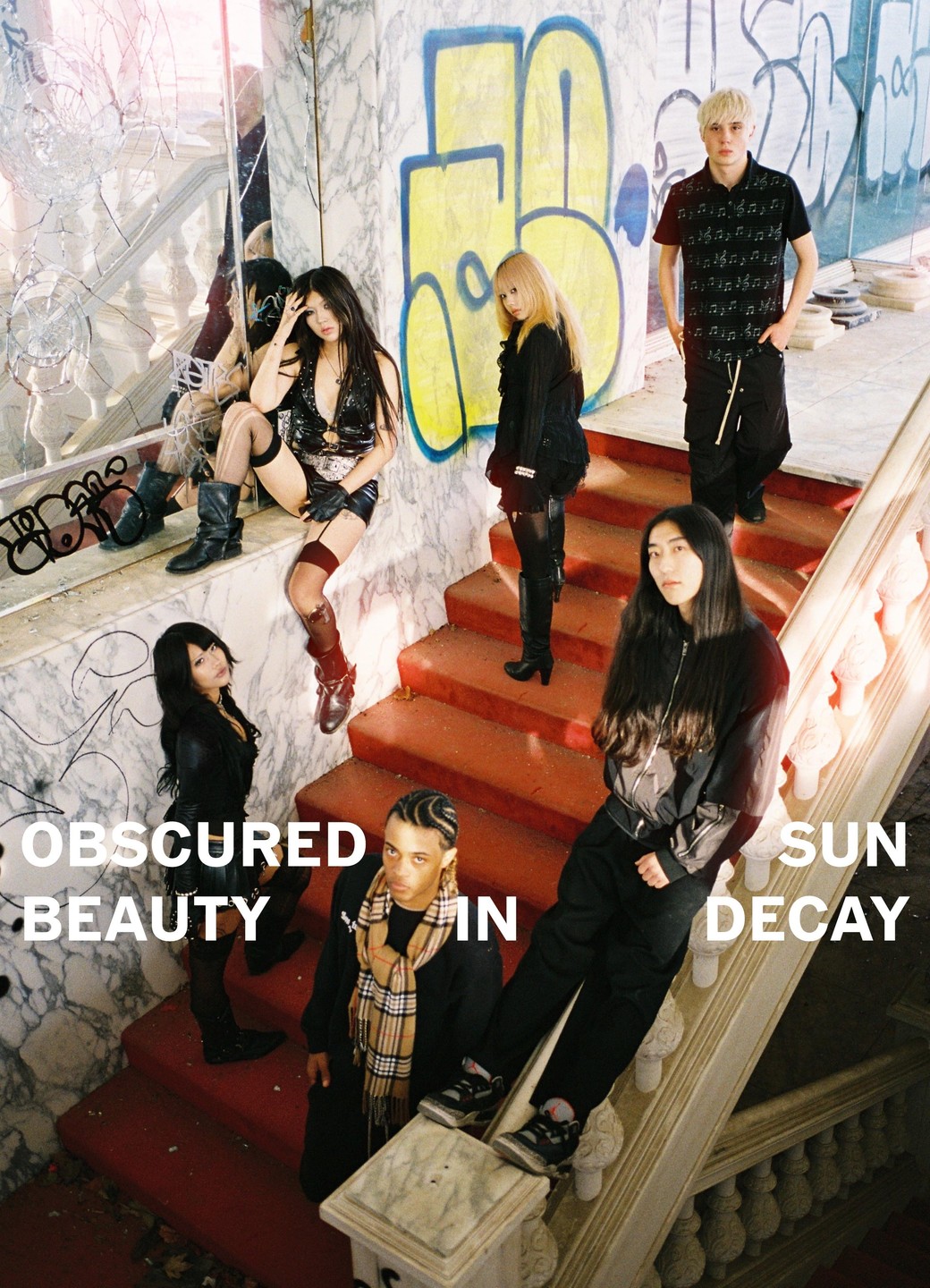 Six people pose on a red staircase and marble landing with graffiti and broken glass.