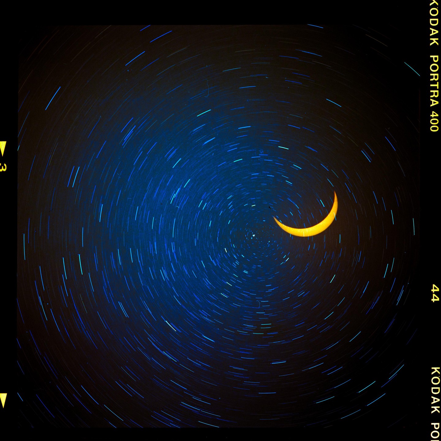 A crescent sun is visible against a dark sky with circular star trails.