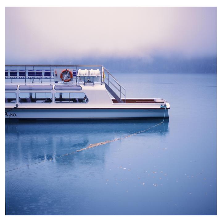 A white boat is docked on a body of water under a hazy sky.