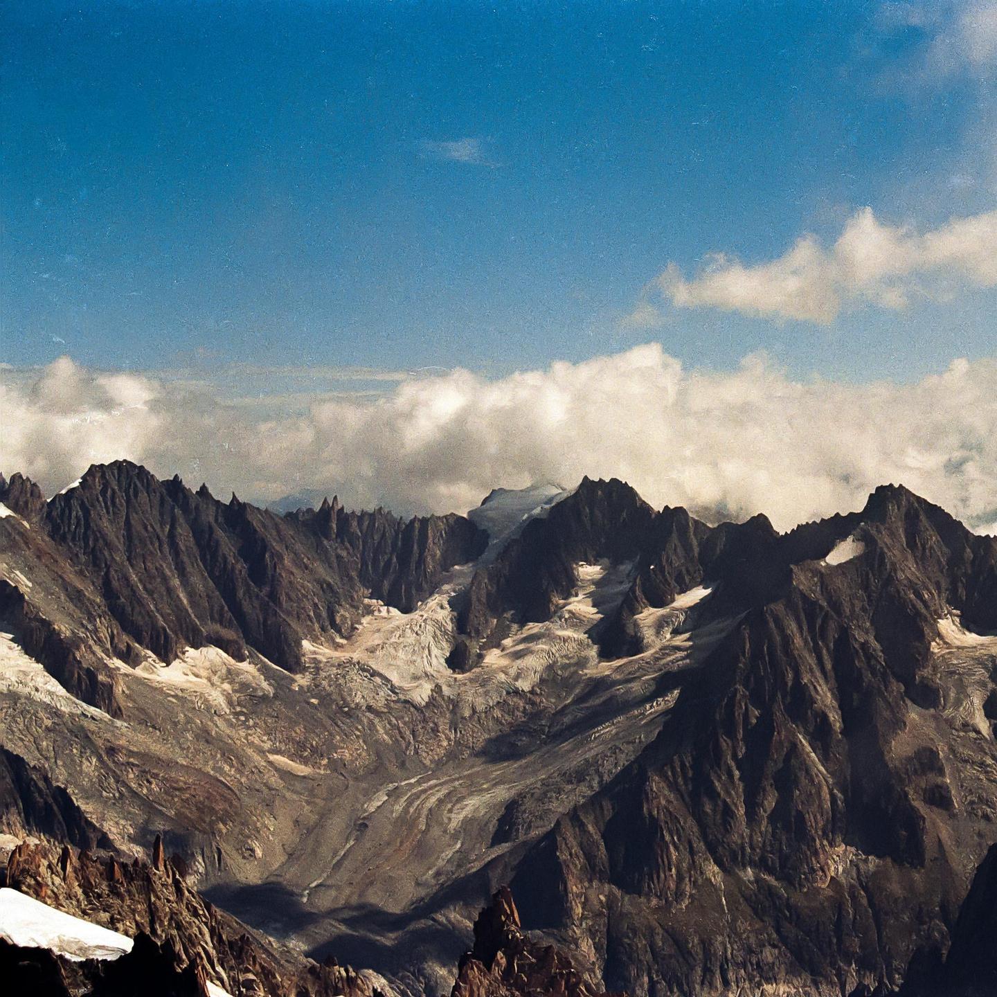 A mountain range with snow and clouds is visible under a blue sky.