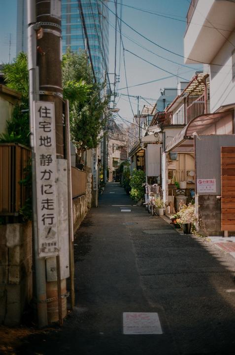 A narrow street with buildings and power lines on either side leads into the distance.