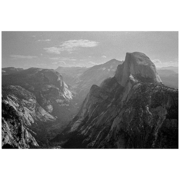 A black and white landscape shows a valley with a prominent rock formation on the right.