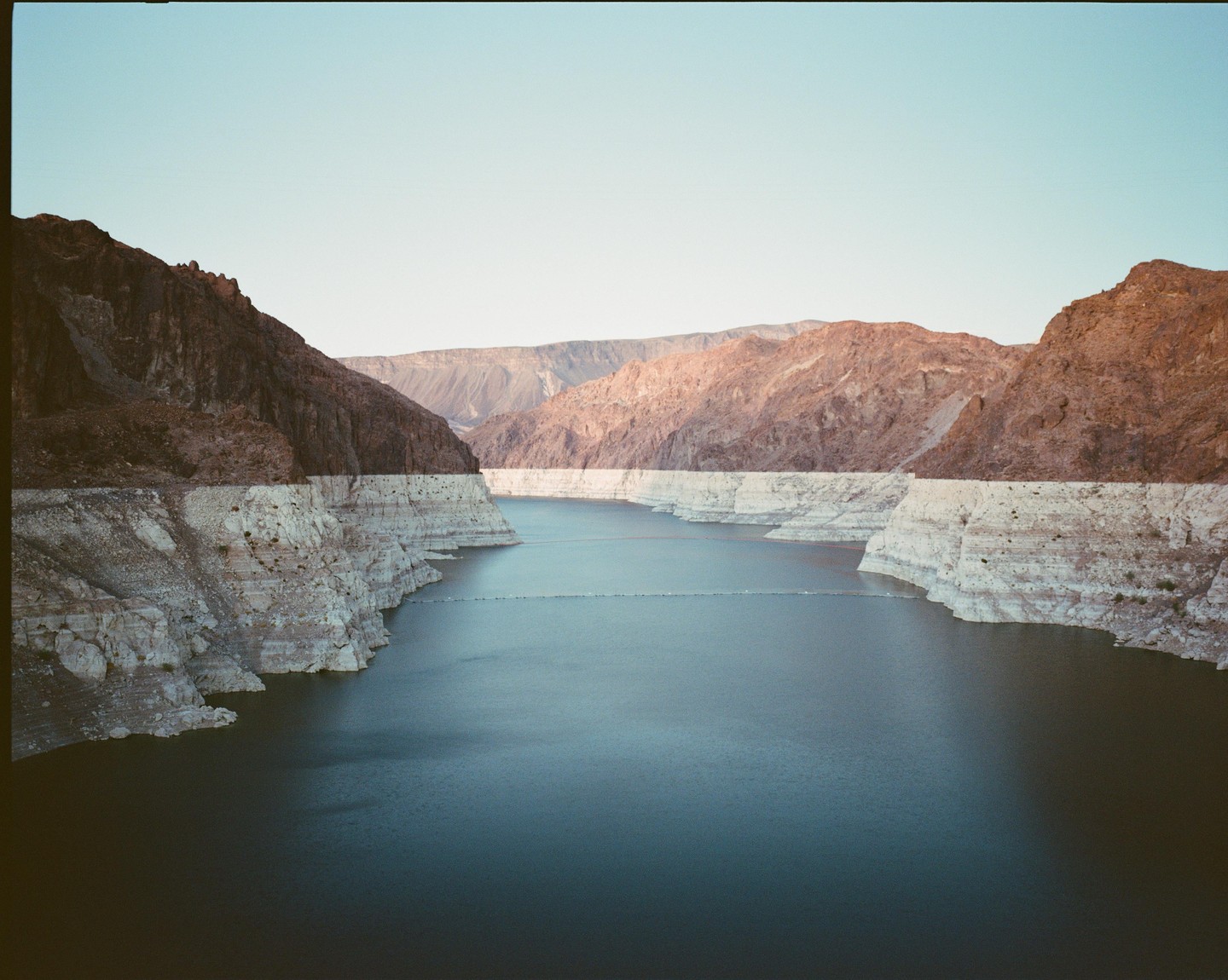 A wide shot shows a body of water surrounded by mountains with a clear sky.