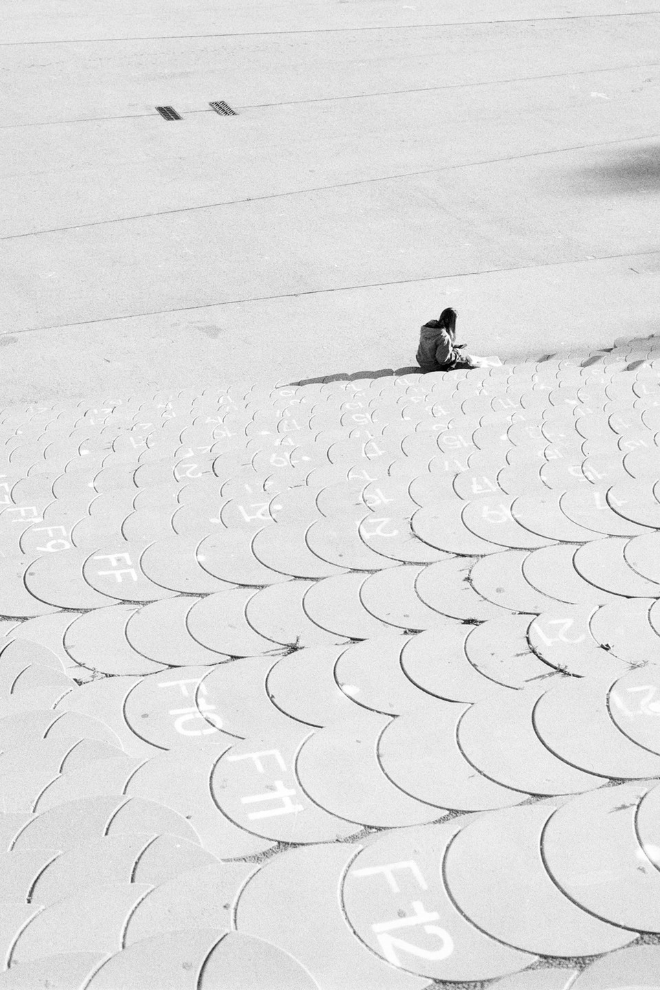 A person sits on a large, textured surface with circular patterns and numbers.
