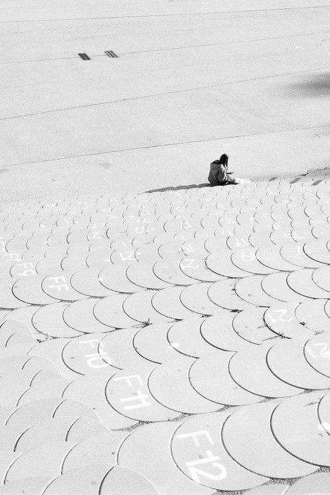 A person sits on a large, textured surface with circular patterns and numbers.