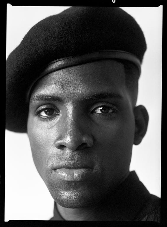 A man wearing a beret looks directly at the viewer.