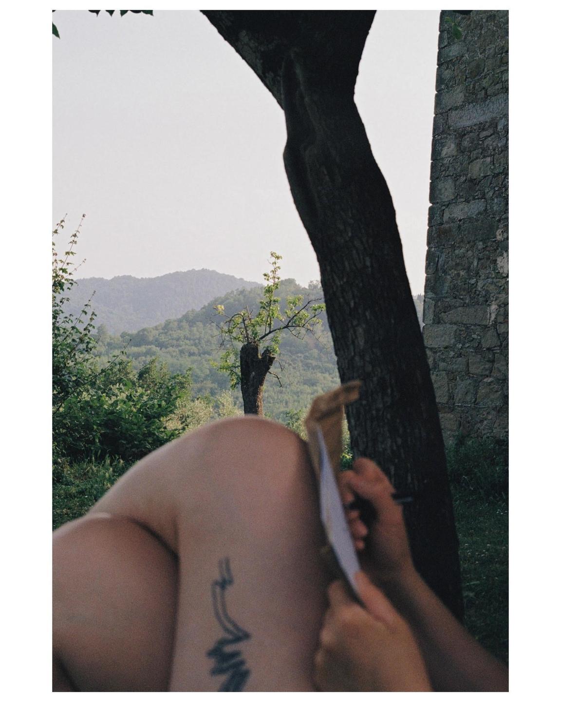 A person is writing a postcard with a mountain landscape in the background.