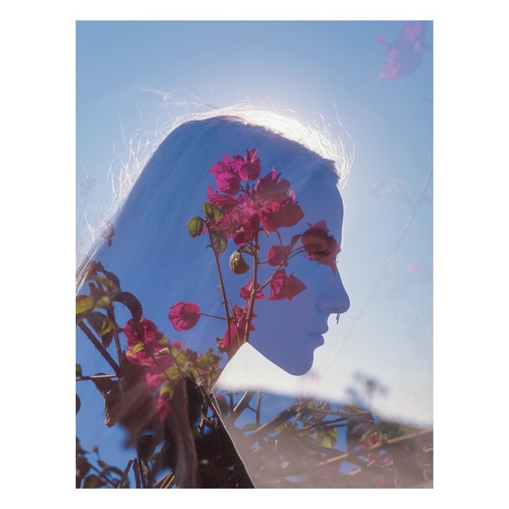 A double exposure shows the profile of a woman overlaid with pink bougainvillea flowers against a bright blue sky.
