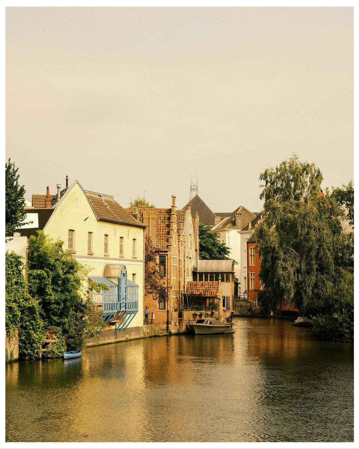 A canal with boats is surrounded by buildings and trees.