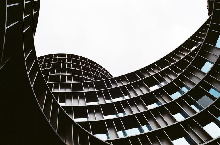 A low-angle view shows the curved facade of a modern building with many windows.