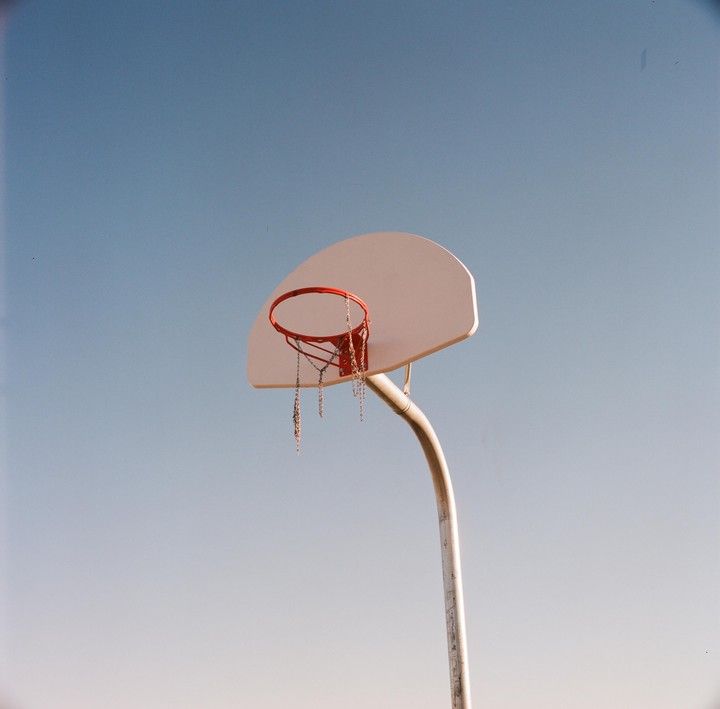 A basketball hoop with a chain net stands against a clear blue sky.