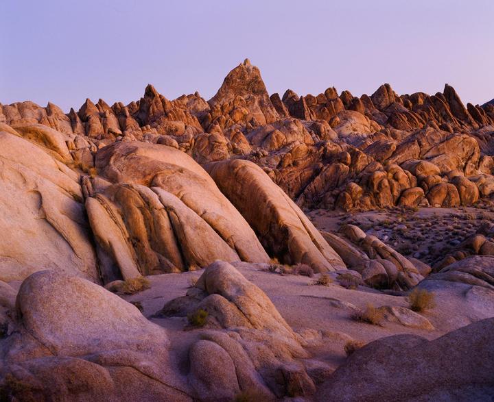 A landscape of rugged rock formations is illuminated by the golden hour light.