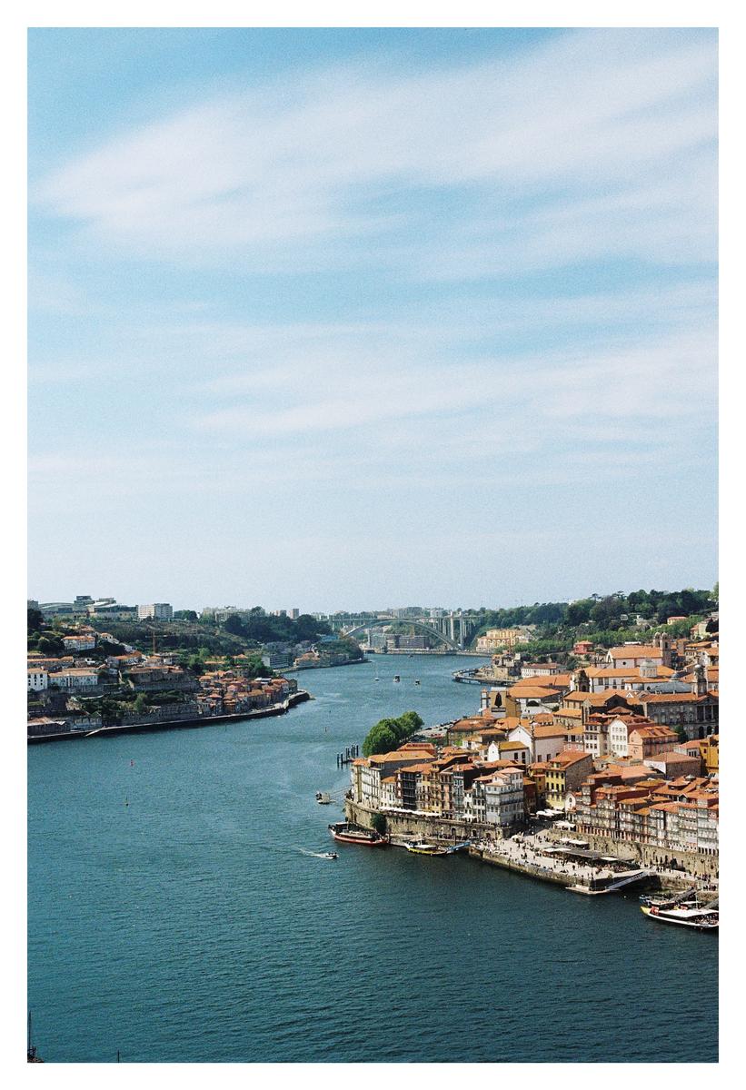 A wide river flows through a city with buildings on both banks and a bridge in the distance.
