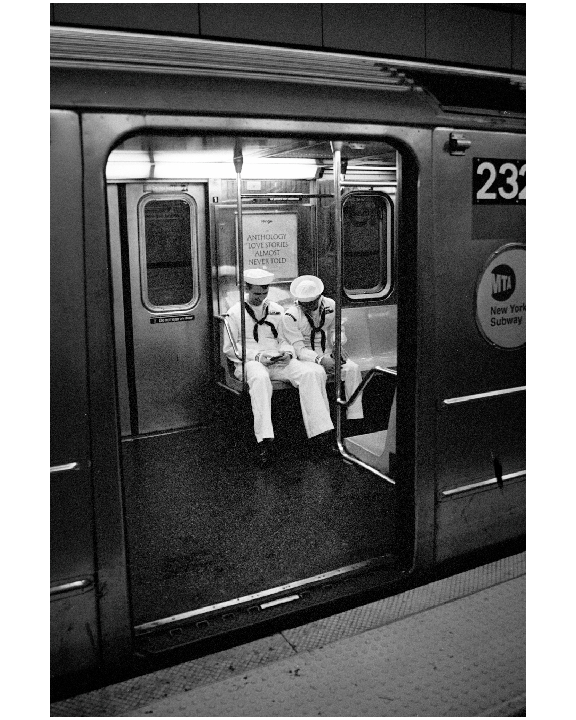 Two men in sailor uniforms sit inside a subway car with an open door.