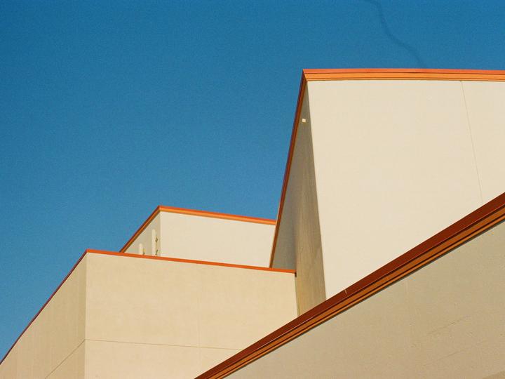 The corner of a building with orange trim is visible against a clear blue sky.