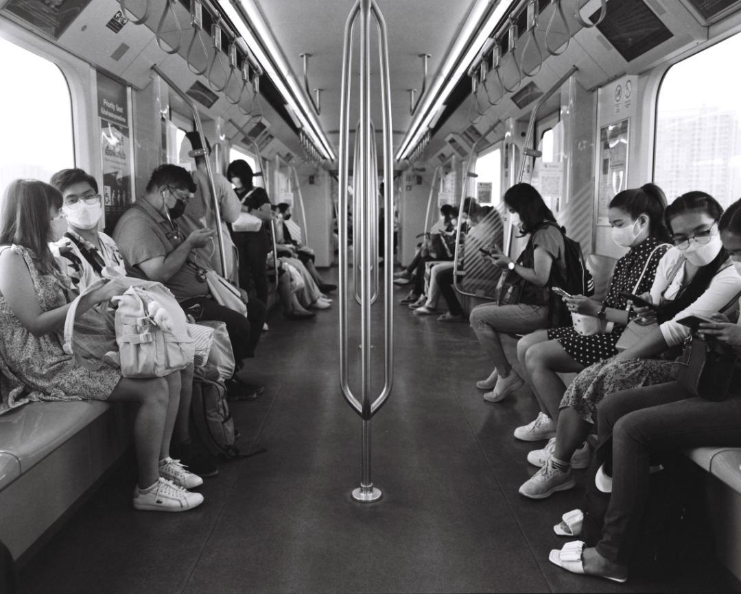 People wearing masks sit inside a train car.
