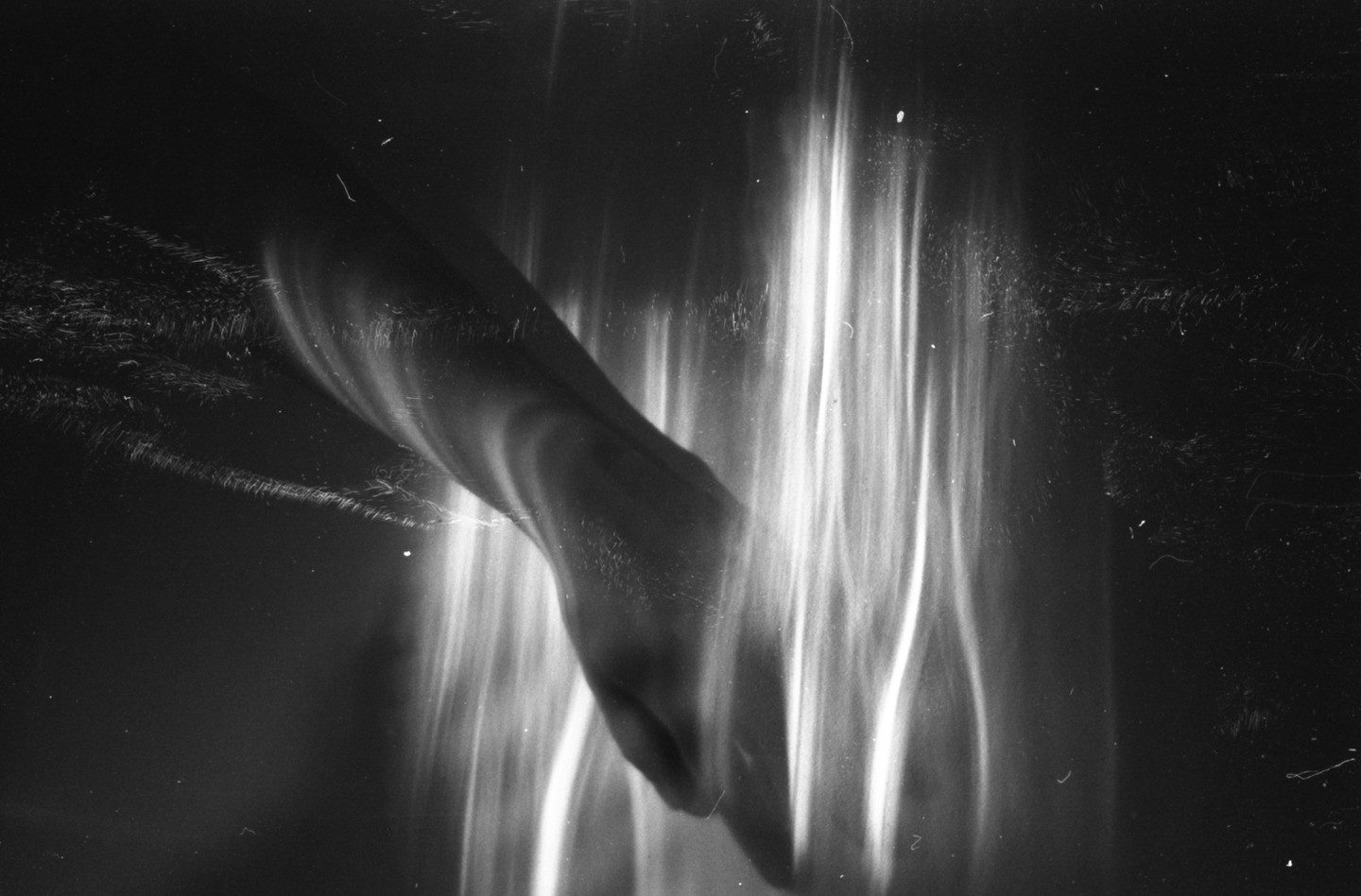 A dark, abstract image shows a hand reaching into vertical streaks of light.