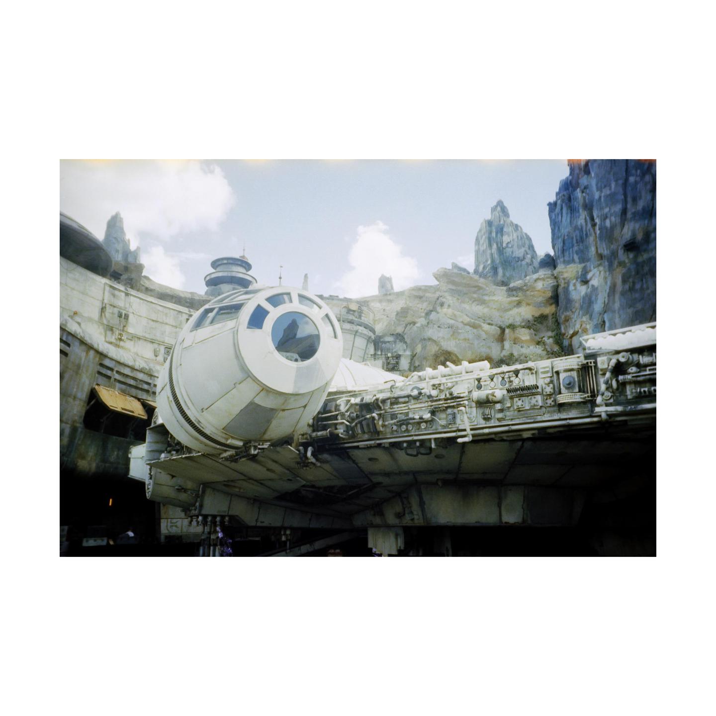 A large spaceship is docked in a rocky, alien landscape under a cloudy sky.