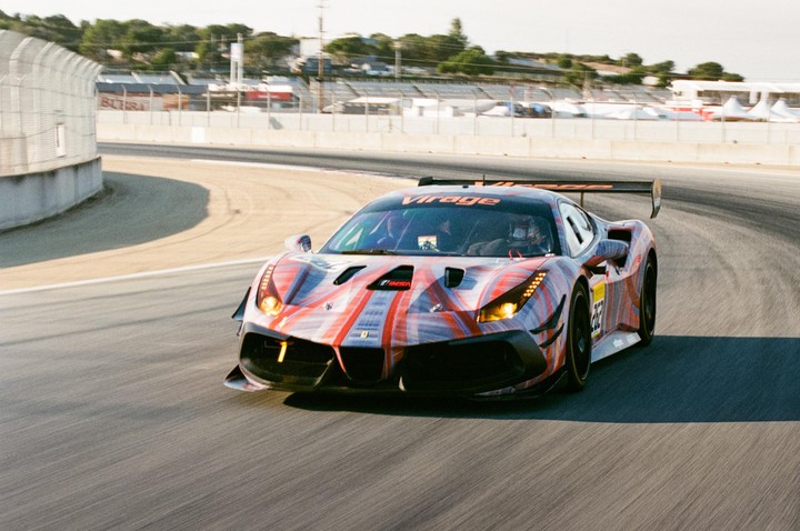 A race car with a colorful abstract paint job speeds around a track.