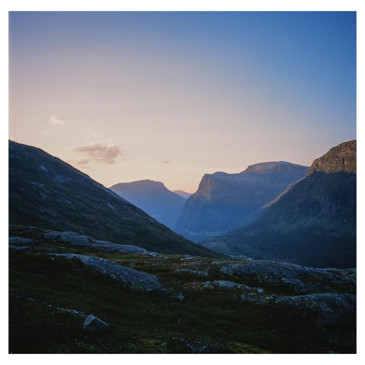 A valley with mountains on either side is illuminated by the setting sun.