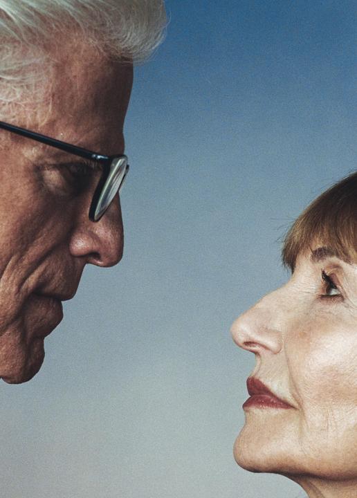 A man and a woman are looking at each other in profile against a blue background.