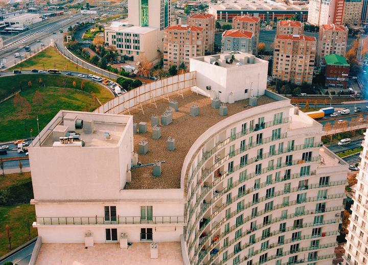 An aerial view shows a curved apartment building next to a highway and other buildings.