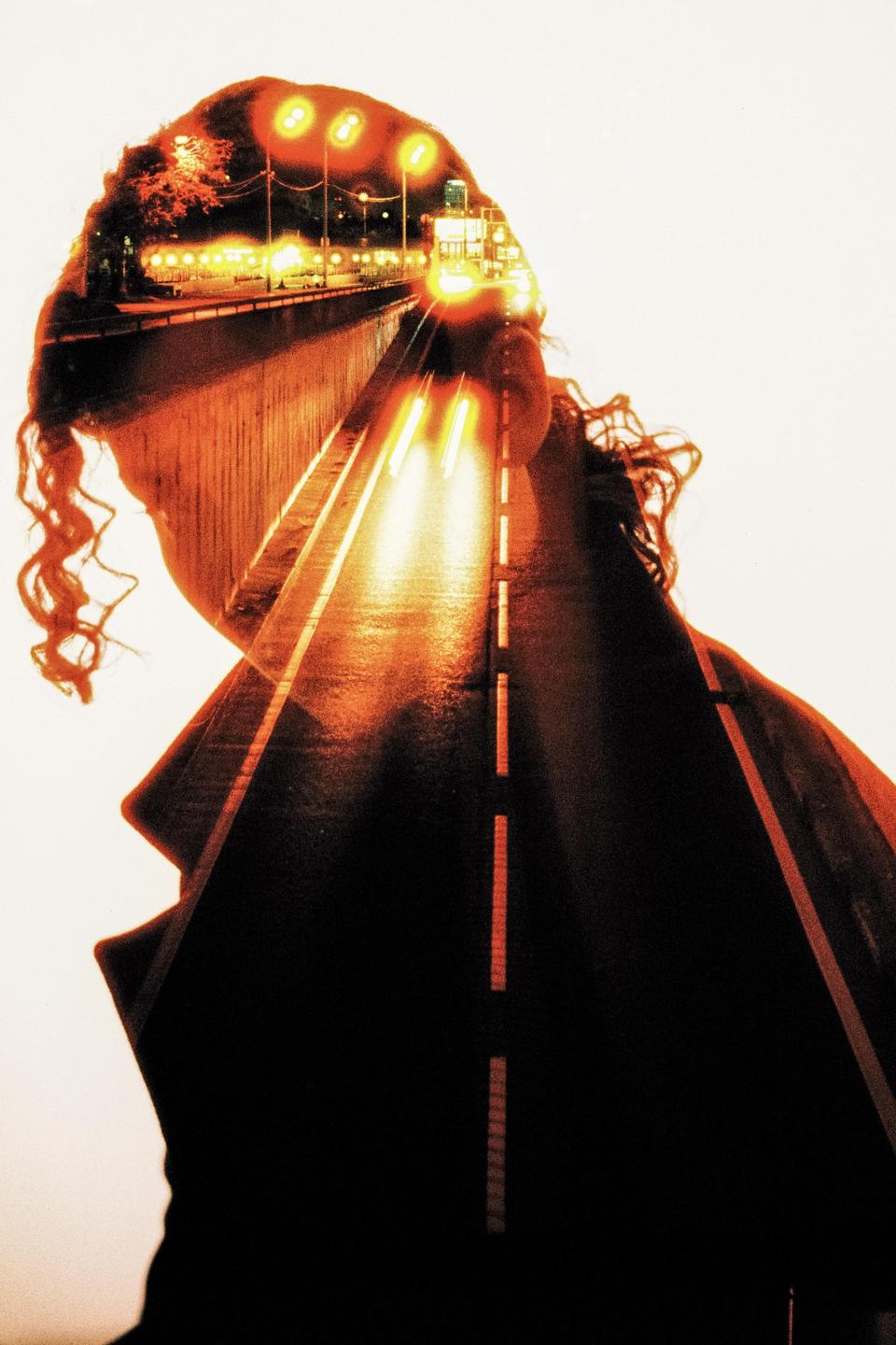 A double exposure shows a woman's silhouette overlaid with a night road scene featuring car headlights and streetlights.