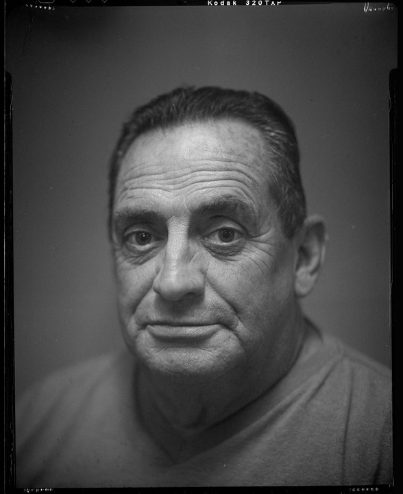 A man with a serious expression looks directly at the viewer in a close-up portrait.