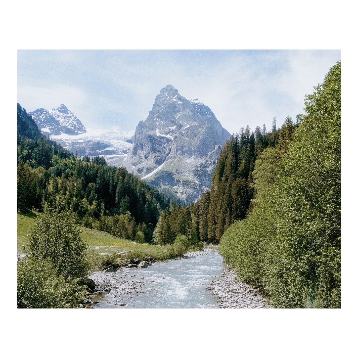 A river flows through a valley with mountains and forests on either side.