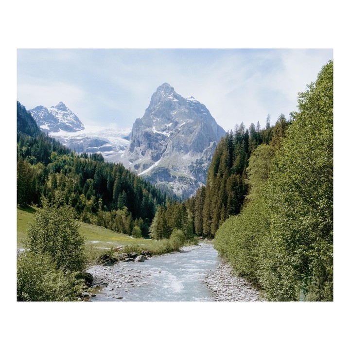 A river flows through a valley with mountains and forests on either side.