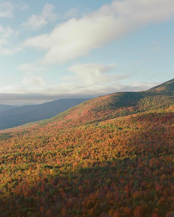 A mountain slope covered in autumn foliage is visible under a partly cloudy sky.
