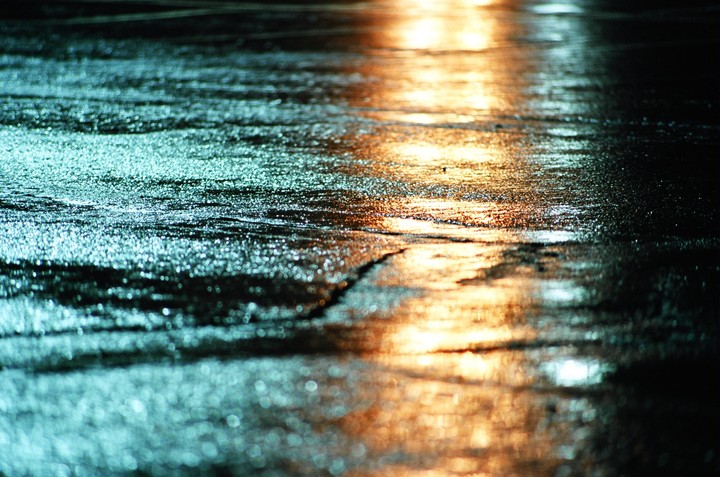 Light reflects off a wet street at night.