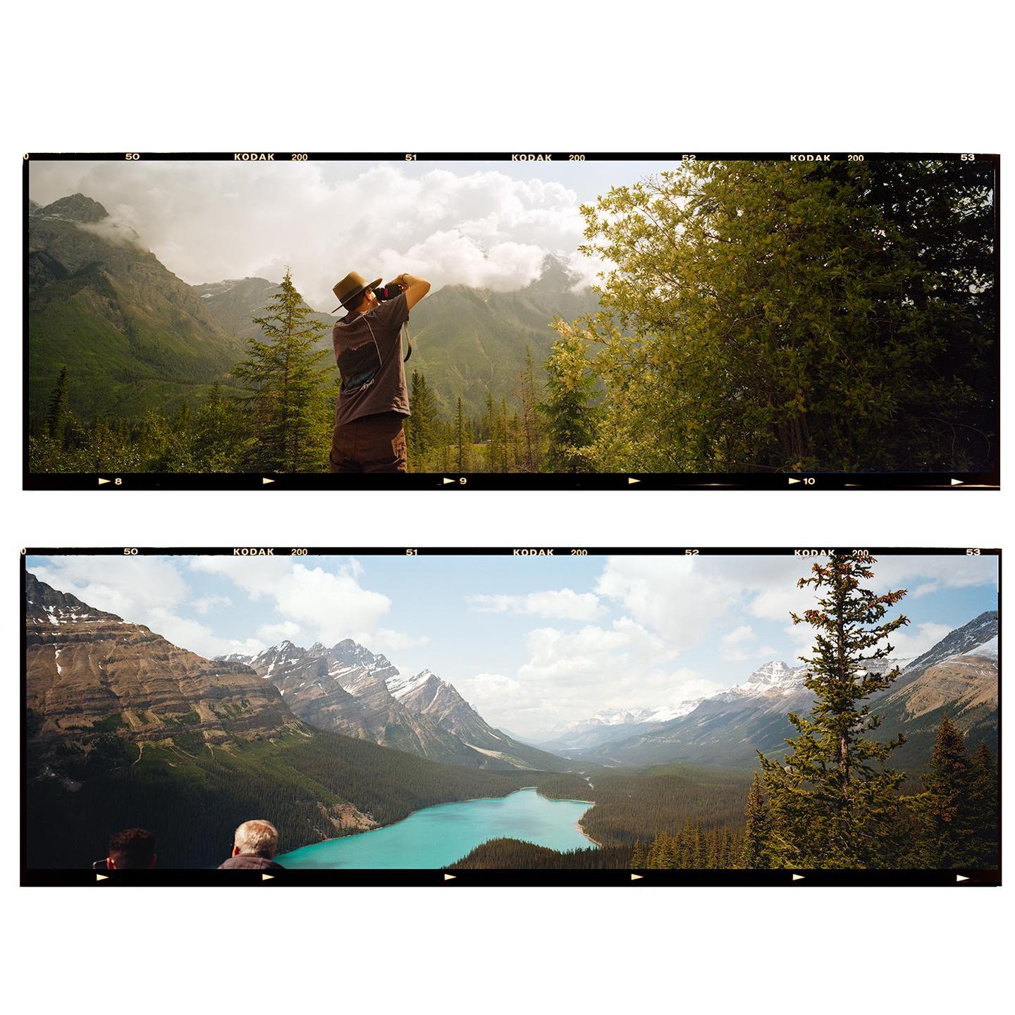 A man photographs a mountain landscape, and two people look out over a turquoise lake surrounded by mountains.