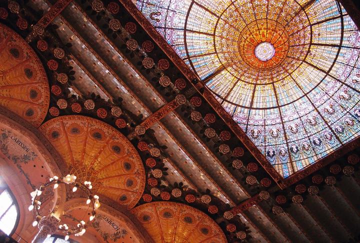 A stained glass dome and ornate ceiling with rose details are visible from below.