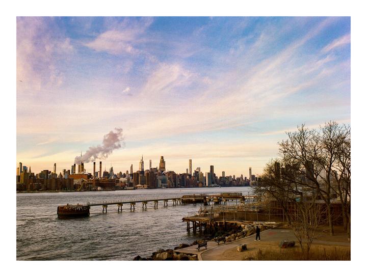A cityscape with a river and a pier in the foreground is visible under a golden hour sky.
