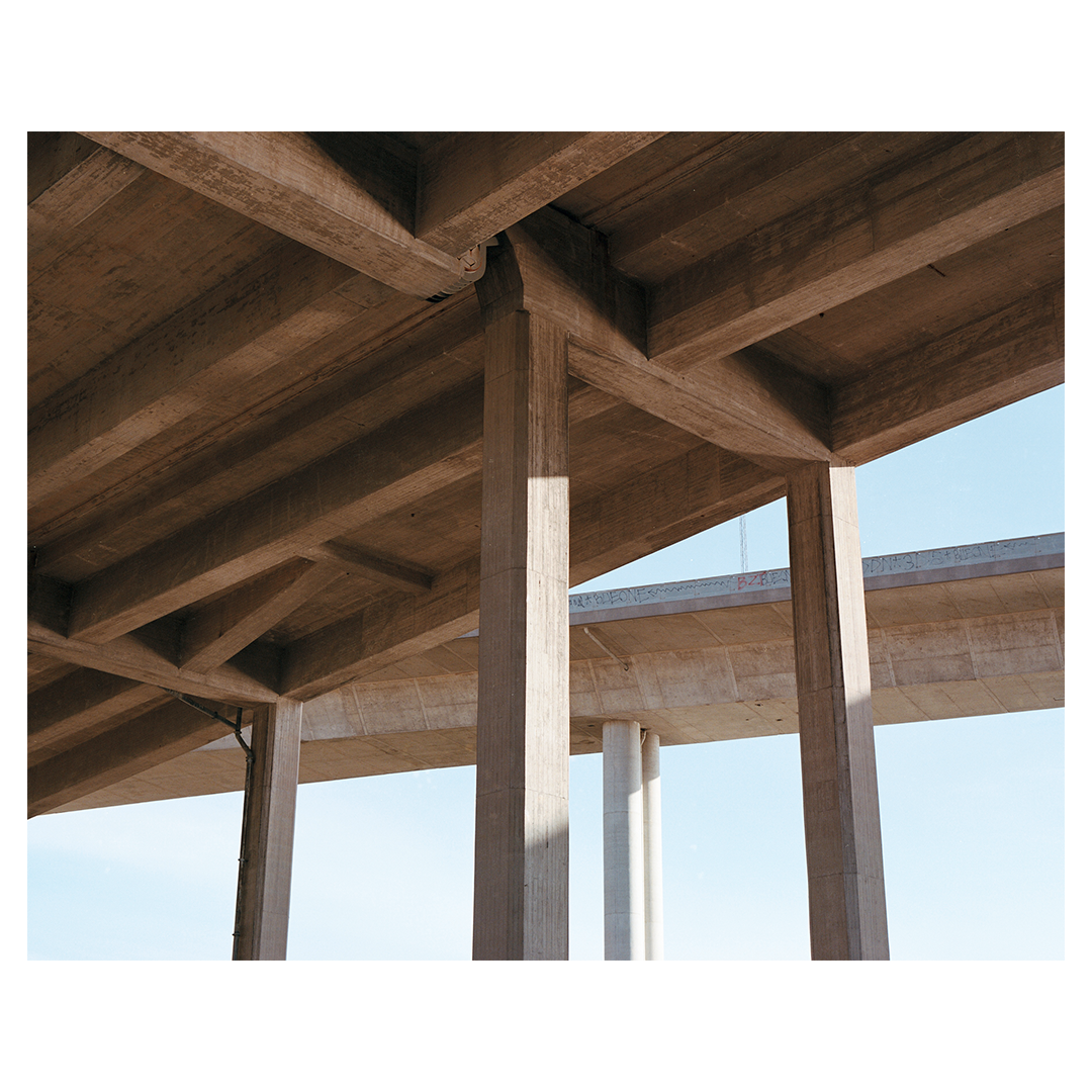 Concrete pillars and beams of an overpass are visible against a clear sky.