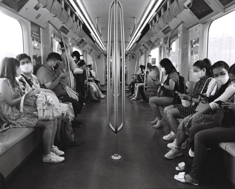 People wearing masks sit inside a train car.