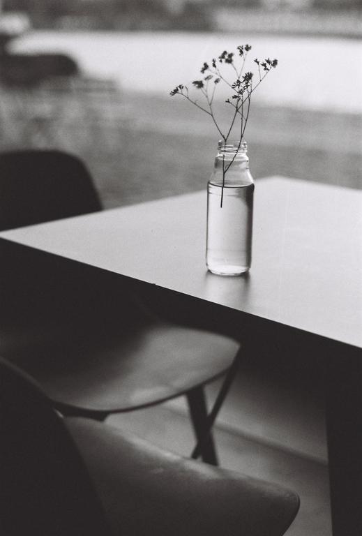 A small bottle with delicate flowers sits on a table next to a chair.