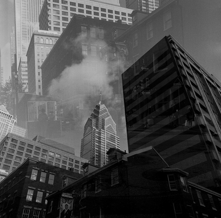 A double exposure shows multiple buildings, including One Liberty Place, with steam rising in the middle ground.