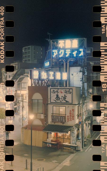 A street corner in Japan is illuminated by neon signs at night.