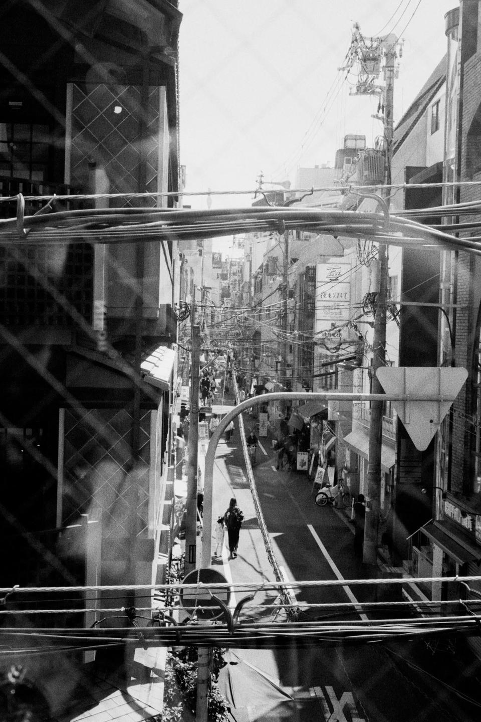 A person walks down a narrow street lined with buildings and power lines.