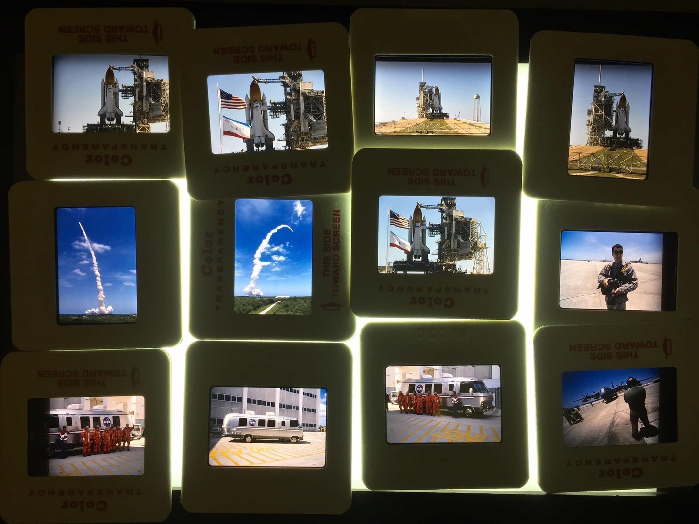 A grid of twelve illuminated slides shows images of space shuttles, astronauts, and support vehicles.
