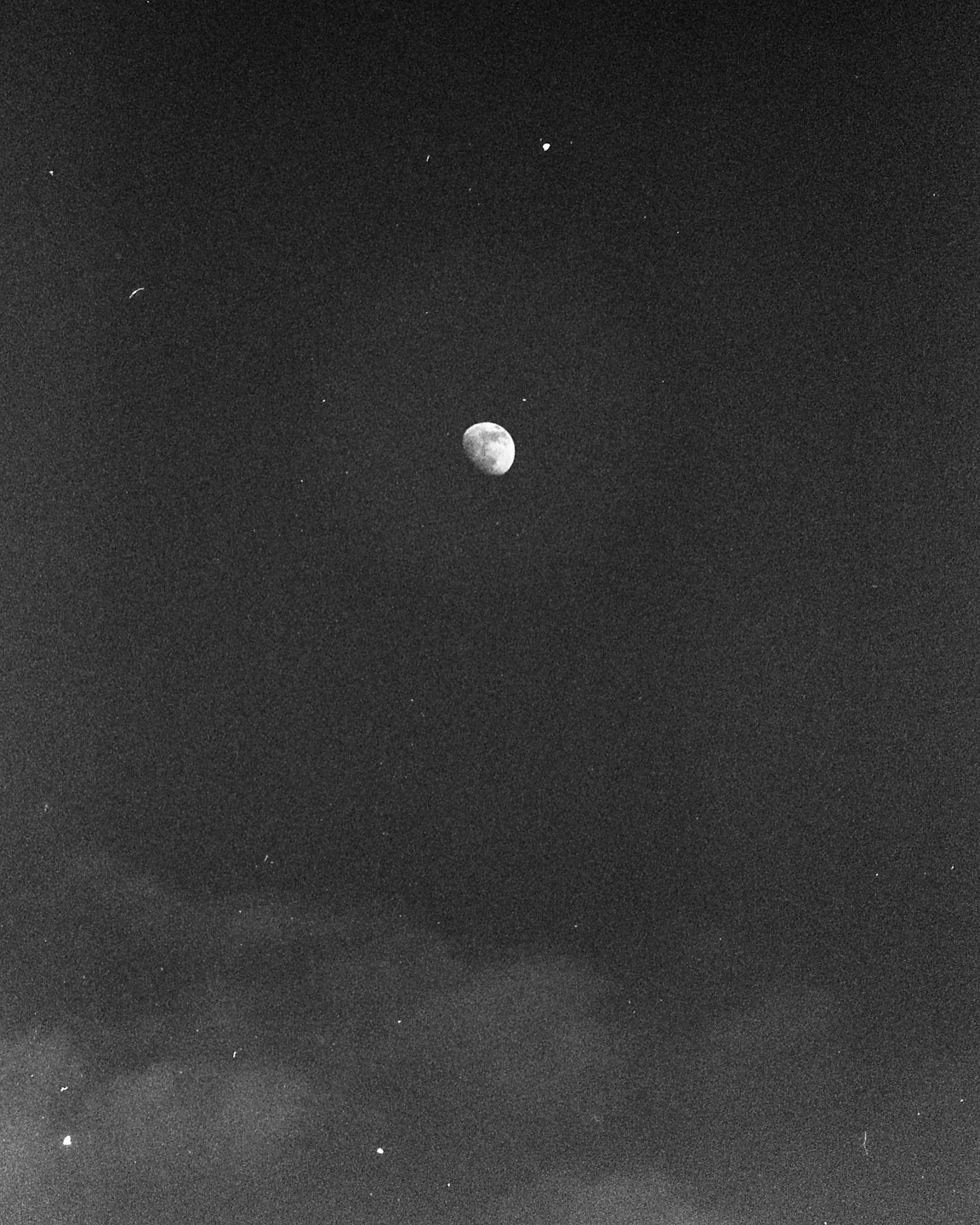 The moon is visible in the night sky with a few stars and some clouds.