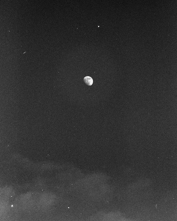 The moon is visible in the night sky with a few stars and some clouds.