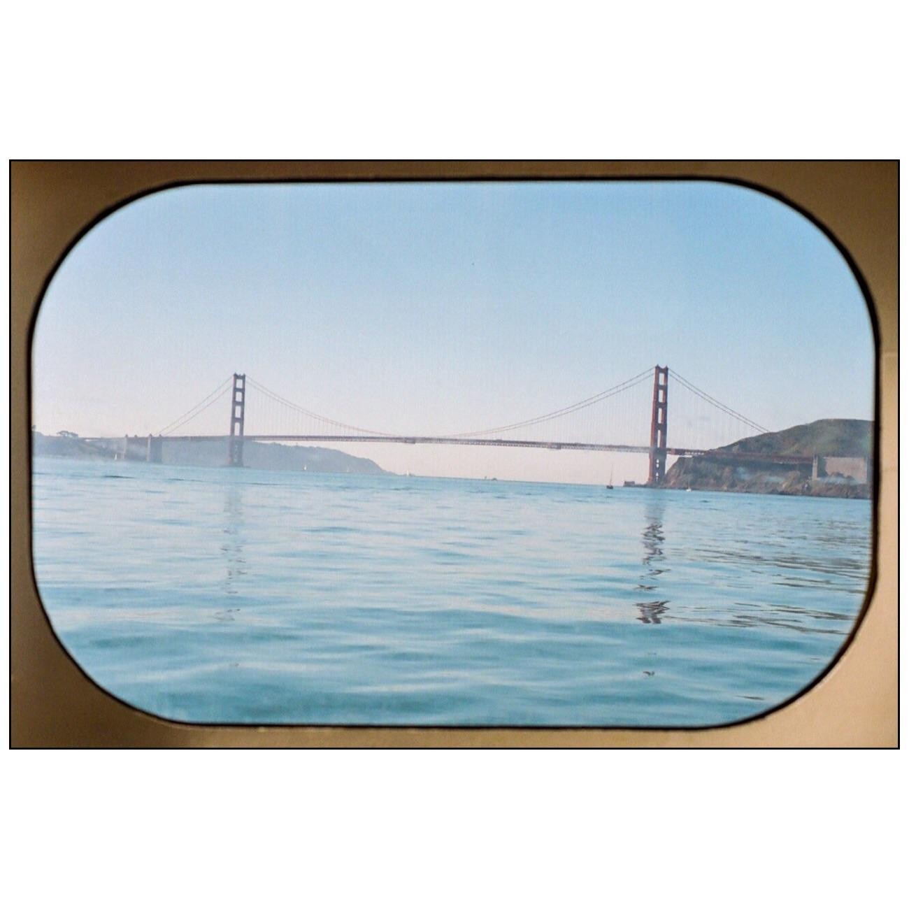 The Golden Gate Bridge is visible across a body of water, framed by a rounded border.
