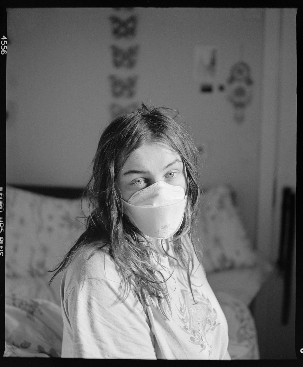 A woman wearing a face mask looks directly at the viewer.