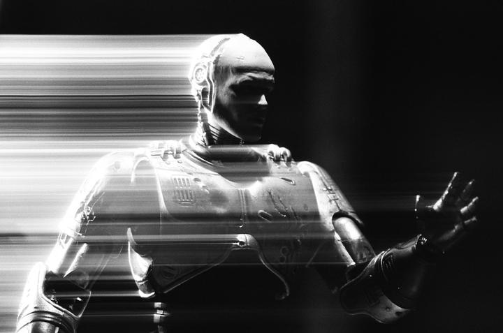 A black and white image shows a Robocop action figure with light trails across the frame.